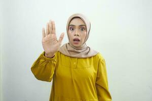 Young Asian Muslim woman standing with outstretched hand showing stop gesture photo