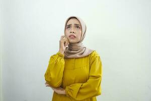 Portrait of thinking young Asian woman looking up and touch chin isolated on over white background photo