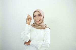 Portrait of smiling young Asian woman looking up and touches her cheek isolated on white background photo