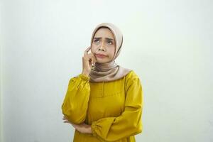 Portrait of thinking young Asian woman looking up and touch chin isolated on over white background photo