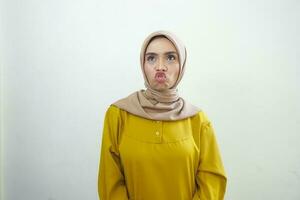 un retrato de un conmocionado asiático mujer vistiendo un mostaza casual vestido, aislado por un blanco antecedentes foto