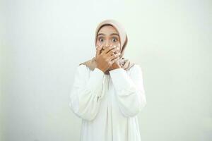 conmocionado joven asiático musulmán mujer vestido en blanco cubierta boca con mano para Error aislado en blanco antecedentes foto
