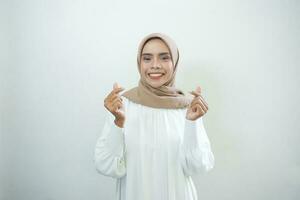 retrato de sonriente asiático musulmán mujer demostración corazón gesto aislado terminado blanco antecedentes foto
