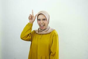 Excited Asian woman wearing casual dress pointing at the copy space upwards, isolated by white background photo