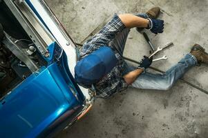 Tired Classic Cars Mechanic Resting on a Garage Floor photo