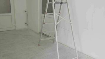A folding staircase stands in a white room in which repairs are being made. video