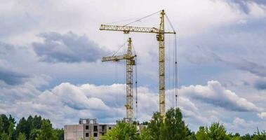 tijd vervallen van twee toren kranen werken Aan bouw met storm pluizig gekruld rollend wolken net zo achtergrond video