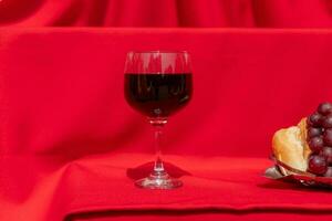 Elements of the last supper of Jesus bread, grapes and wine on a red cloth with harsh lighting photo