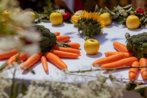 apples, carrots and broccoli on a white table with a white tablecloth photo