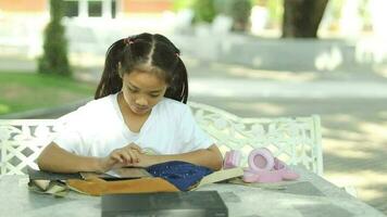 contento asiático niña leyendo libro en el jardín. educación concepto. video