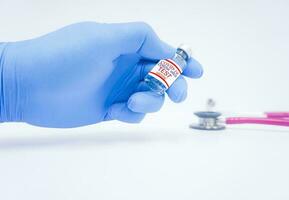 Covid 19 vaccine development test sample At the doctor wearing blue gloves, put the vial on the table and have a stethoscope Blur in the background.Vaccine of fight against coronavirus Concept. photo