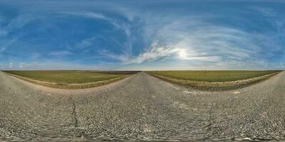 spherical 360 hdri panorama on old asphalt road with cracks with clouds and sun on blue sky in equirectangular seamless projection, as sky replacement in drone panoramas, skybox game development photo