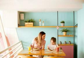 Mother and daughter having a breakfast with fresh squeezed juices in the cafe photo