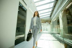 bonito joven negocio mujer caminando con maletín en el oficina pasillo foto