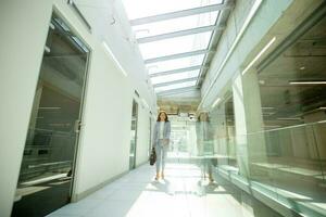 Pretty young business woman walking with briefcase in the office hallway photo