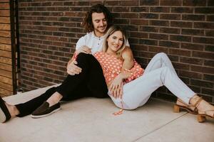 Smiling young couple in love in front of house brick wall photo
