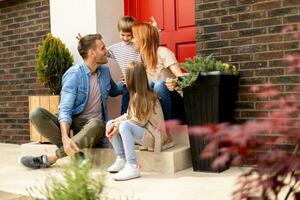 Family with a mother, father, son and daughter sitting outside on the steps of a front porch of a brick house photo