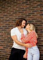 Smiling young couple in love in front of house brick wall photo