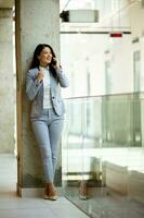 Young business woman using mobile phone in the office hallway photo