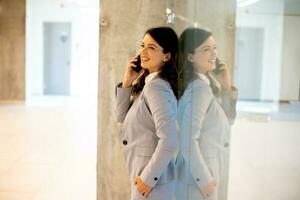 Young business woman using mobile phone in the office hallway photo