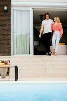 Young couple woling down on stairs by the swimming pool in the house backyard photo