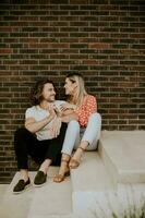 Smiling young couple in love sitting in front of house brick wall photo