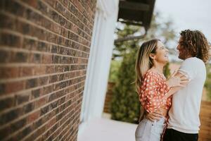 Smiling young couple in love in front of house brick wall photo