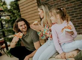 Young family eating pizza in the house backyard photo