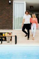 Young couple woling down on stairs by the swimming pool in the house backyard photo