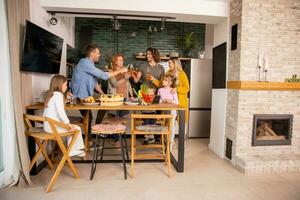 Two families toasting with cider while preparing dinner in the kitchen photo