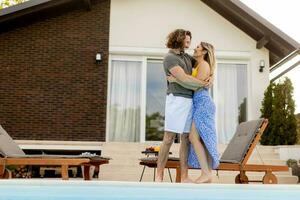 Young couple relaxing by the swimming pool in the house backyard photo