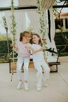 Cute little girls on the swing in the house backyard photo