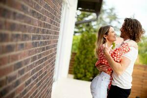 Smiling young couple in love in front of house brick wall photo