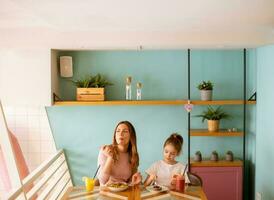 madre y hija teniendo un desayuno con Fresco exprimido jugos en el café foto