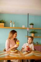 madre y hija teniendo un desayuno con Fresco exprimido jugos en el café foto