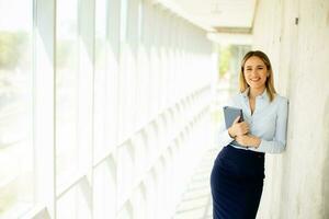 Young business woman holding with notebook in the office hallway photo