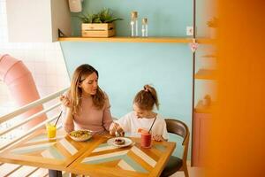 madre y hija teniendo un desayuno con Fresco exprimido jugos en el café foto