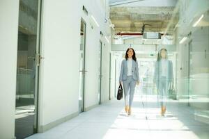 Pretty young business woman walking with briefcase in the office hallway photo