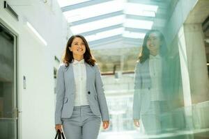 Pretty young business woman walking with briefcase in the office hallway photo