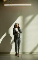 Young business woman using mobile phone in the office hallway photo