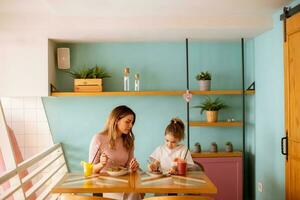 madre y hija teniendo un desayuno con Fresco exprimido jugos en el café foto