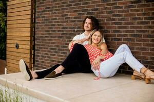 sonriente joven Pareja en amor en frente de casa ladrillo pared foto