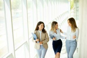 Three young business women walking on stairs in the office hallway photo