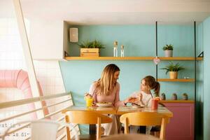 Mother and daughter having a breakfast with fresh squeezed juices in the cafe photo