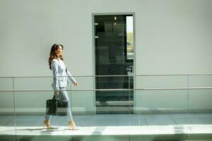 Pretty young business woman walking with briefcase in the office hallway photo