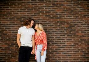 Smiling young couple in love in front of house brick wall photo