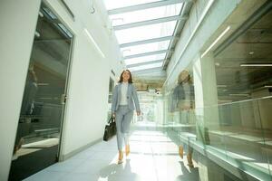 Pretty young business woman walking with briefcase in the office hallway photo