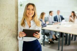 Young business woman with digital tablet in the office hallway photo