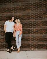 Smiling young couple in love in front of house brick wall photo