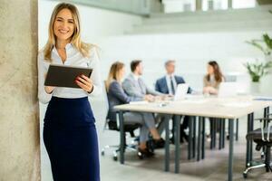 Young business woman with digital tablet in the office hallway photo